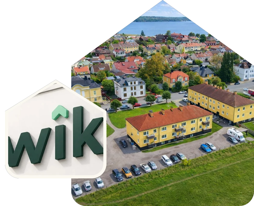 Flygvy över Mariefred vid Mälaren och Wikbos skylt på husfasaden, båda i gavelform